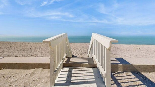 A wooden staircase leading to a beach with a clear blue sky. - Dog-friendly home w/access to Englewood Beach, WIFI, and outdoor patio (Englewood)