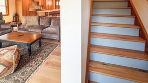 A wooden interior with a staircase, a sofa, and a coffee table. - Camp Ridgewood- Spacious 6-bedroom house in lovely Bolton Landing with AC (Bolton Landing)