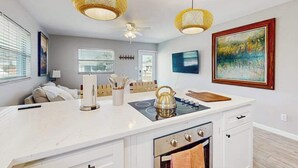 Una cucina moderna con isola centrale, ventilatore a soffitto e illuminazione a sospensione.