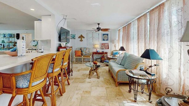 Ein modernes Wohnzimmer mit einer Couch, Sesseln, einem Couchtisch und einem Essbereich mit Bar.