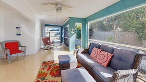 A sunlit room with a ceiling fan, wicker furniture, and a view of a backyard. - Coastal retreat steps to the beach with screened lanai and bikes (Englewood)