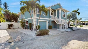 A two-story house with a front porch, a garage, and a staircase leading to the second floor. - Coastal retreat steps to the beach with screened lanai and bikes (Englewood)