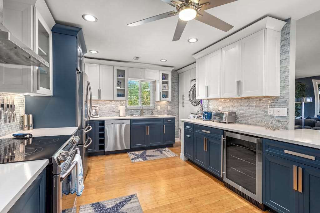 A modern kitchen with dark blue cabinets, stainless steel appliances, and a large island.