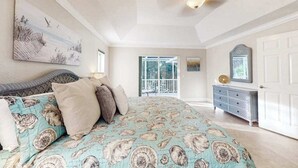 Ein Schlafzimmer mit einem Bett, einem Deckenventilator, einer Kommode und einer Tür.