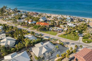 An aerial view of a coastal residential area with houses, roads, and a beach. - Charming beachside duplex steps to the Gulf with bikes and coastal views (Englewood)