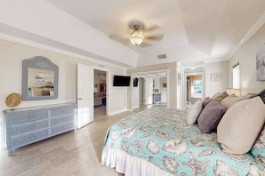 A bedroom with a bed, dresser, and a television. - Charming beachside duplex steps to the Gulf with bikes and coastal views (Englewood)