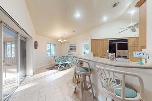 A spacious kitchen with a bar area, a dining set, and a view of the outdoors. - Charming beachside duplex steps to the Gulf with bikes and coastal views (Englewood)