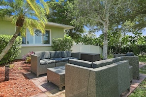 A patio with wicker furniture, a palm tree, and a house in the background. - Spacious property with separate living quarters, pool, & lanai - dog-friendly (Venice)