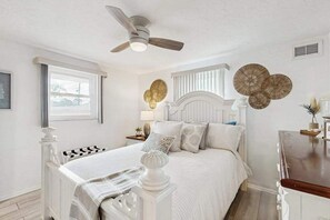 Ein Schlafzimmer mit Bett, Deckenventilator, Fenster und Wanddekoration.