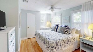 A bedroom with a bed, a ceiling fan, a television, a dresser, and a window with curtains. - Dog-friendly duplex with outdoor living area - walk to beach/downtown (Venice)