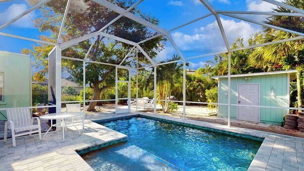 A covered swimming pool with a white roof, surrounded by a patio with chairs and a small table. - Dog-friendly duplex with outdoor living area - walk to beach/downtown (Venice)