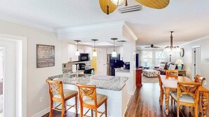 A spacious kitchen with a central island, wooden chairs, and a dining area with a table and chairs. - Home with private pool, enclosed yard, patio, sunroom, AC, & W/D (Venice)
