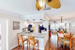 A spacious kitchen with a central island, wooden chairs, and a dining area with a table and chairs. - Home with private pool, enclosed yard, patio, sunroom, AC, & W/D (Venice)