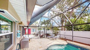 A covered outdoor swimming pool with lounge chairs and a patio area. - Home with private pool, enclosed yard, patio, sunroom, AC, & W/D (Venice)
