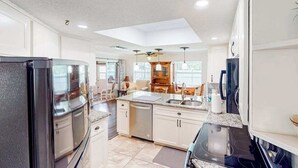 A modern kitchen with a central island, built-in appliances, and a dining area with a view. - Home with private pool, enclosed yard, patio, sunroom, AC, & W/D (Venice)