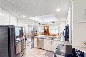 A modern kitchen with a central island, built-in appliances, and a dining area with a view. - Home with private pool, enclosed yard, patio, sunroom, AC, & W/D (Venice)