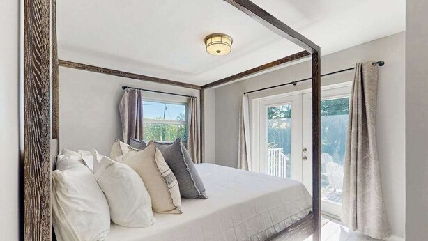 Ein Schlafzimmer mit Bett, Fenster, Tür und Deckenleuchte.