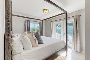A bedroom with a bed, a window, a door, and a ceiling light. - Coastal duplex with full kitchen, close to beach & shopping (Naples)