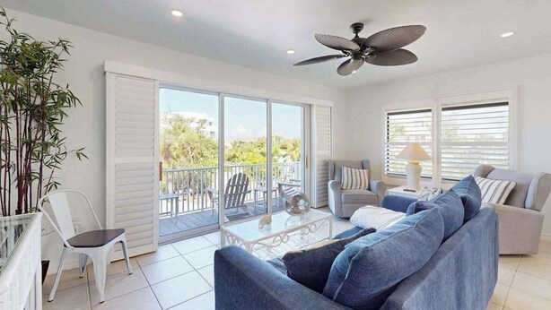 A spacious living area with a ceiling fan, a sofa, a coffee table, and a balcony with outdoor furniture. - Spacious Duplex with two kitchens, W/D, and WiFi throughout (Englewood)