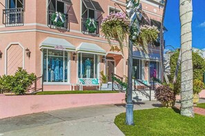 A pink building with a storefront, a staircase, and a palm tree. - Beautiful home w/ heated in ground pool, wifi, dog-friendly, and sundeck (Naples)