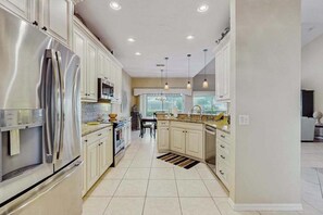 A modern kitchen with white cabinetry, stainless steel appliances, and pendant lighting. - Beautiful home w/ heated in ground pool, wifi, dog-friendly, and sundeck (Naples)