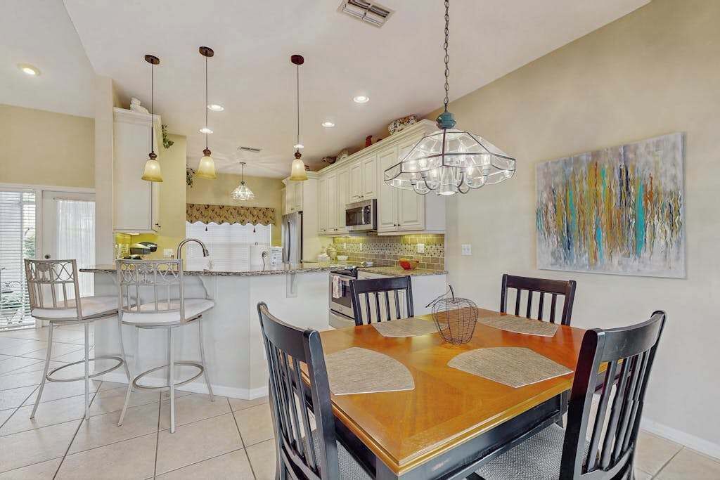 A spacious kitchen with white cabinets, a central island, and pendant lighting.