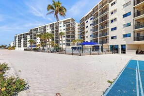 Ein Strandhotel mit mehreren Etagen, Balkonen und einem Schwimmbad.