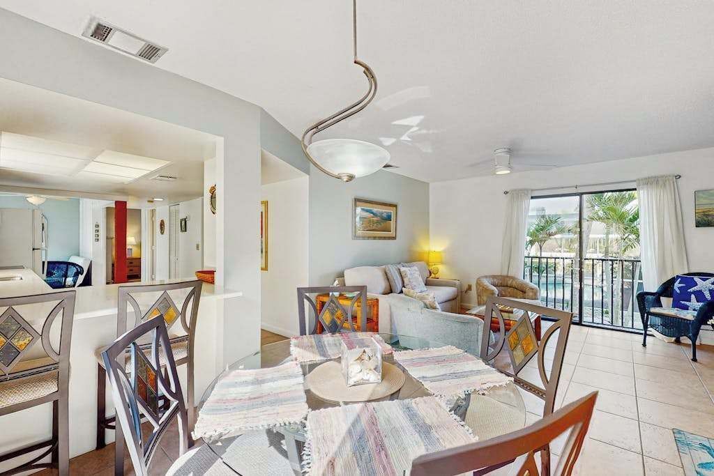 A dining area with a round table, chairs, and a hanging light fixture.