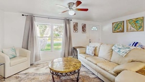 A living room with a sofa, a round coffee table, a ceiling fan, and artwork on the walls. - Relax, Swim & Explore! A Dog-Friendly Private Pool Retreat Close to Everything! (Port Charlotte)
