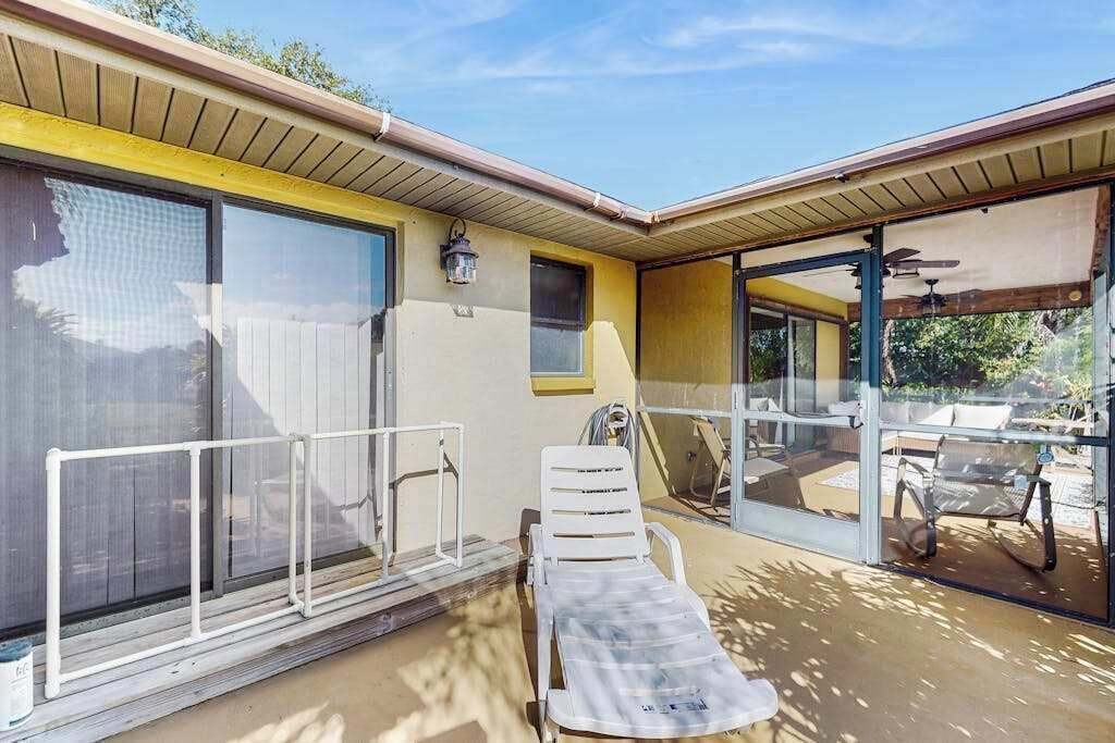 Un espacio exterior cubierto con piscina, una silla de descanso y un ventanal que da a un patio.