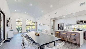 A modern kitchen with a central island, bar stools, and a dining area with white chairs. - Custom-built home with private patio, central AC, & W/D - dog-friendly (Port Charlotte)