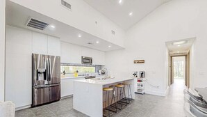 A modern kitchen with a central island, stainless steel appliances, and a bar stool seating area. - Custom-built home with private patio, central AC, & W/D - dog-friendly (Port Charlotte)