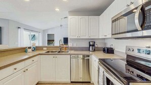 A modern kitchen with white cabinets, stainless steel appliances, and a dishwasher. - Spacious home with private saltwater heated pool, gas grill, close to the beach (Venice)