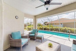 A covered outdoor area with wicker furniture, a pool, and a view of the surrounding landscape. - Spacious home with private saltwater heated pool, gas grill, close to the beach (Venice)