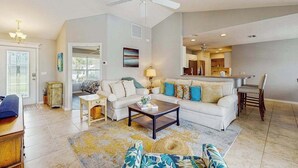 A living room with a sofa, coffee table, and a dining area with a chair. - Spacious home with private saltwater heated pool, gas grill, close to the beach (Venice)
