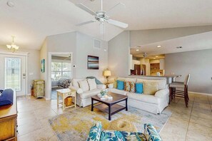 A living room with a sofa, coffee table, and a dining area with a chair. - Spacious home with private saltwater heated pool, gas grill, close to the beach (Venice)