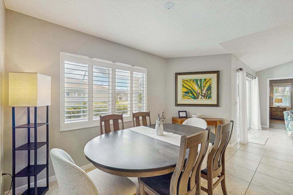 Un coin repas avec une table ronde, des chaises, une lampe et un tableau au mur.