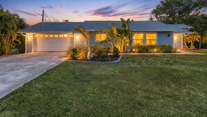 A residential house with a garage, a well-maintained lawn, and a clear sky. - Spacious coastal Pet friendly home close to beaches and shopping. (Port Charlotte)