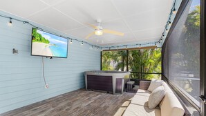 A covered patio with a TV, ceiling fan, hot tub, and outdoor seating. - Spacious coastal Pet friendly home close to beaches and shopping. (Port Charlotte)