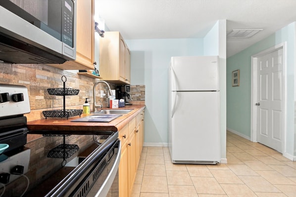 A kitchen with a stove, oven, microwave, and a refrigerator. - Dog-friendly and Snowbird friendly close to beaches! (Venice)