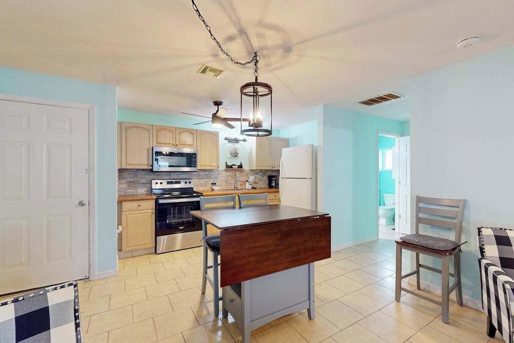 A modern kitchen with a dining area, a ceiling fan, and a view into another room. - Dog-friendly and Snowbird friendly close to beaches! (Venice)