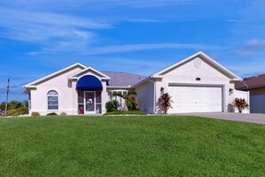 A single-story house with a garage, a covered entryway, and a well-maintained lawn. - Coastal Cottage with private pool, lanai, and free internet (Port Charlotte)