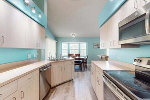A modern kitchen with light wood cabinets, a built-in oven, and a dining area with a window. - Coastal Cottage with private pool, lanai, and free internet (Port Charlotte)