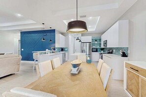 Eine moderne Küche mit weißen Schränken, einer blauen Akzentwand und Pendelleuchten.