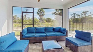A sunlit room with a large window, wicker furniture, and a ceiling fan. - Well appointed new home with private pool, large yard, W/D & dog friendly (Rotonda West)
