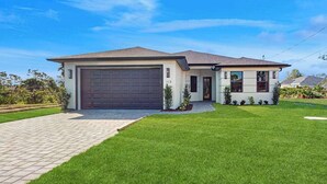 A single-story house with a garage, a well-maintained lawn, and a clear sky. - Well appointed new home with private pool, large yard, W/D & dog friendly (Rotonda West)