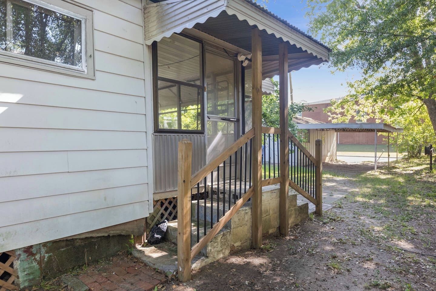 A wooden porch with a railing, a window, and a door leading to a covered area.