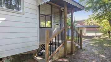 A wooden porch with a railing, a window, and a door leading to a covered area.