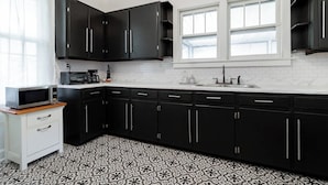 A kitchen with black cabinets, a white countertop, a microwave, a coffee maker, and a clock on the wall. - Casa Blanca|Near Ft Benning|Pet Friendly|King Bed (Columbus)