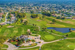 A golf course with a clubhouse, a pond, and surrounding residential areas. - Coastal home on golf course w/ water view, private pool & spa, AC, W/D, Wifi (Rotonda West)